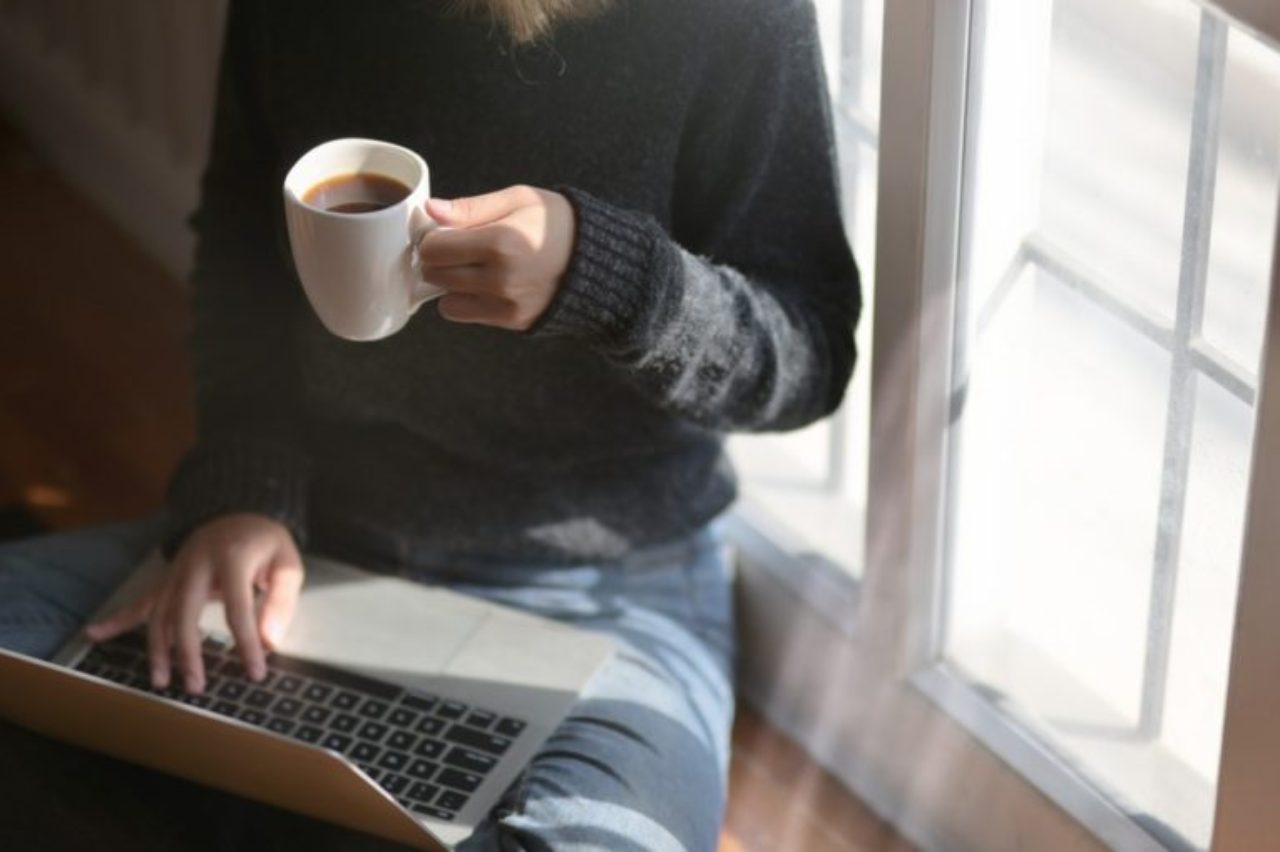 femme-utilisant-ordinateur portable-tout-en-tenant-une-tasse-de-café-3759083