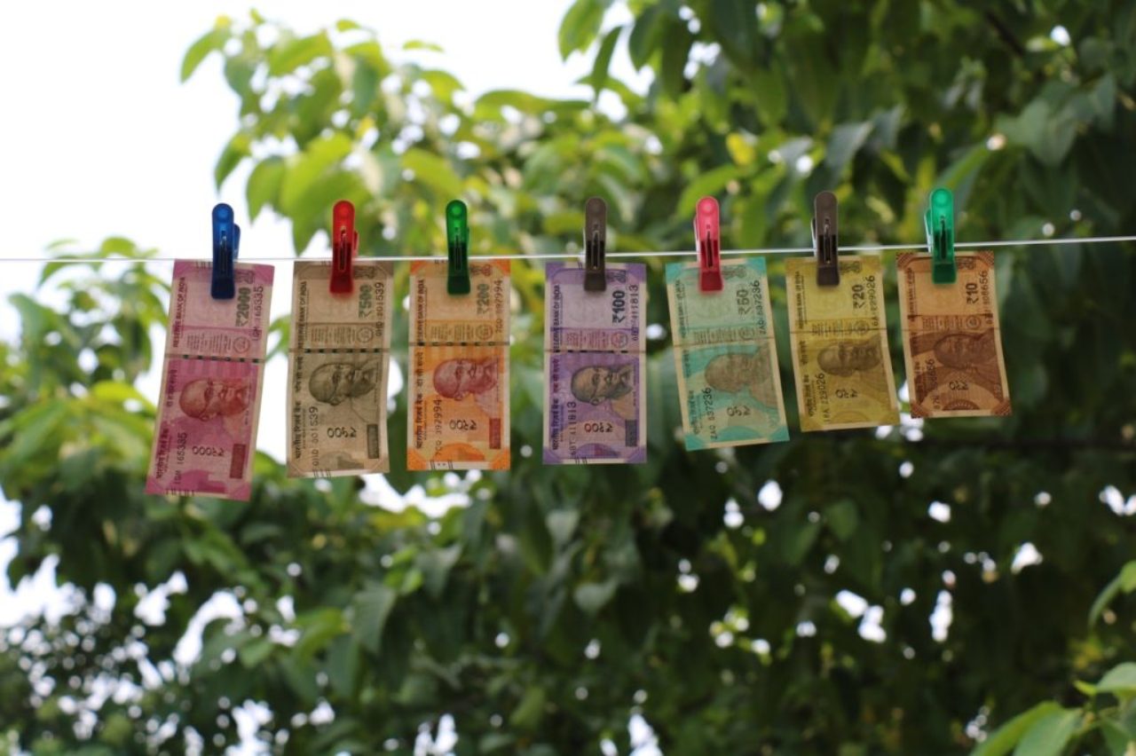 sept billets de banque indiens en roupies suspendus à une corde à linge sur des pinces à linge